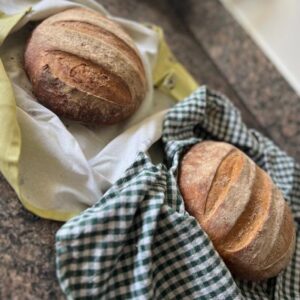 Two sourdough loaves handmade at the Artisan School of Food, wrapped in tea towels.