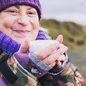Me clutching a cup of hot chocolate with all the trimmings, wearing my camouflage Dry-Robe and my bright purple woolly hat